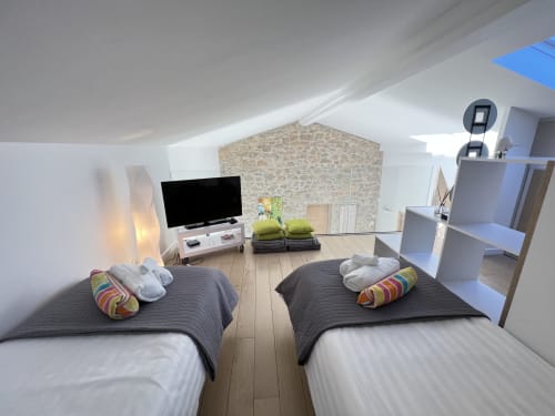 Chambre moderne sous les combles de la villa de Cap d'Antibes avec deux lits, TV et mobilier contemporain