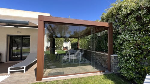 Terrasse vitrée moderne avec mobilier de salle à manger à la villa Cap d'Antibes, vue sur la piscine et les jardins paysagés