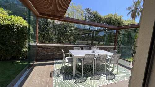 Élégant espace de restauration sous pergola moderne à Villa La Cabane à Cap d'Antibes, avec table blanche, chaises et vue sur un jardin verdoyant