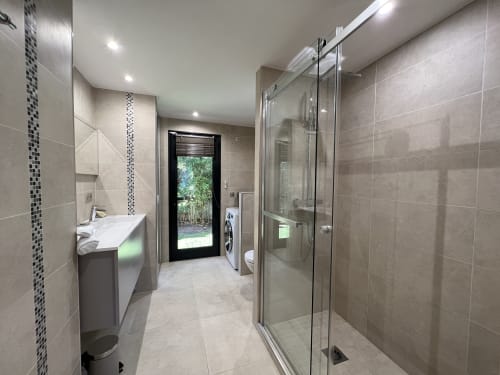 Salle de bains moderne avec douche à l'italienne, vasque, et porte donnant sur le jardin à la Villa La Cabane, Cap d'Antibes
