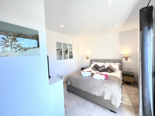 Chambre moderne avec lit gris, appliques murales et vue sur la piscine à Villa La Cabane à Cap d'Antibes