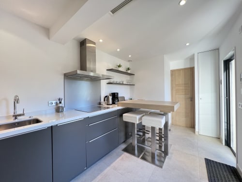 Cuisine moderne avec îlot à Villa La Cabane, Cap d'Antibes, mobilier sombre et plan de travail blanc