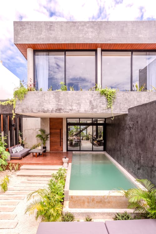 Villa moderna de Tulum con piscina turquesa, deck de madera, zona de descanso y exuberante vegetación tropical