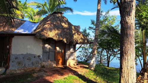 Bungaló rústico con techo de paja en el hostal Cayuco Maya en Bacalar, México, con vista al lago
