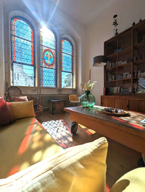 Élégante bibliothèque de La Maison D'olivier avec vitraux, bureau en bois, rayonnages et lumière colorée
