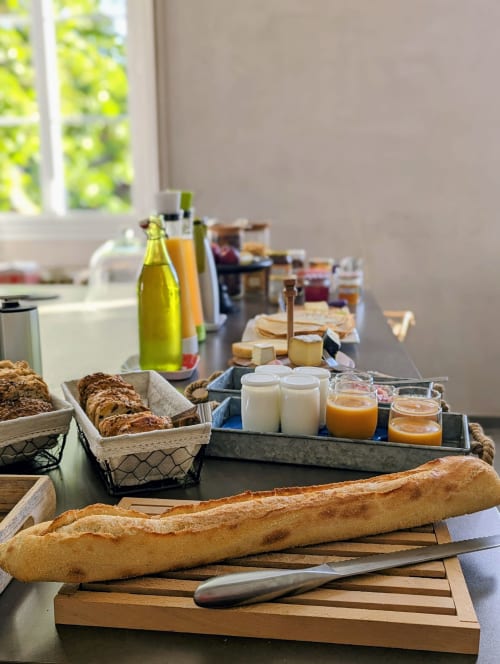 Petit-déjeuner continental à La Maison D'olivier avec baguettes fraîches, pâtisseries, fromages, confitures et jus de fruit