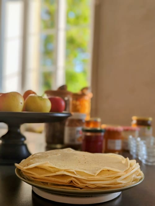 Crêpes sur assiette avec pommes, confitures et lumière matinale à La Maison D'olivier B&B