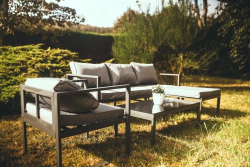 Salon de détente moderne en plein air au jardin d'Etretat, hôtel Art de Voyager avec haies et paysage verdoyant.
