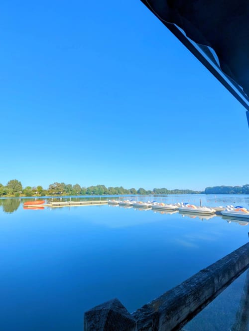 Lac tranquille avec bateaux amarrés et rive bordée d'arbres à La Maison D'olivier, Mesnard La Barotière