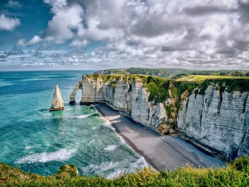 Falaises blanches dramatiques et arche naturelle à Étretat, France avec mer turquoise et plage de sable