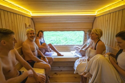 Groupe se détendant dans un sauna en bois avec vue sur la fenêtre à l'hôtel Art De Voyager à Étretat, France