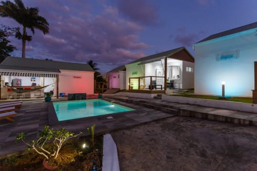 Kaz A Bibi BnB à Sainte-Rose avec piscine illuminée, petits bungalows colorés et palmiers au crépuscule