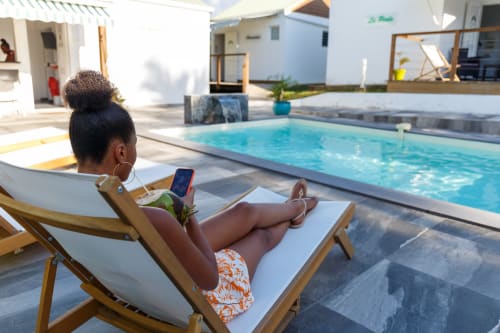 Femme relaxant dans une chaise longue au bord de la piscine de l'hôtel Kaz A Bibi à Sainte-Rose, Guadeloupe