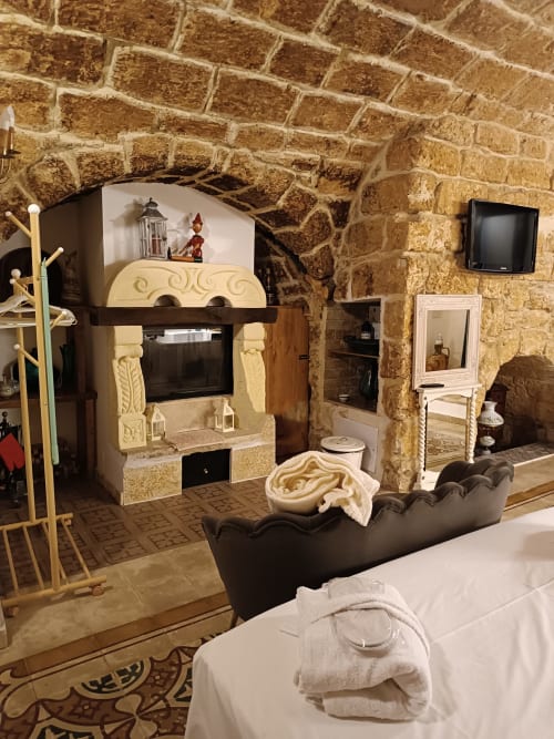 CorteLirice Paradiso Sottano 1 apartment interior with stone walls, fireplace, TV, black sofa and bed