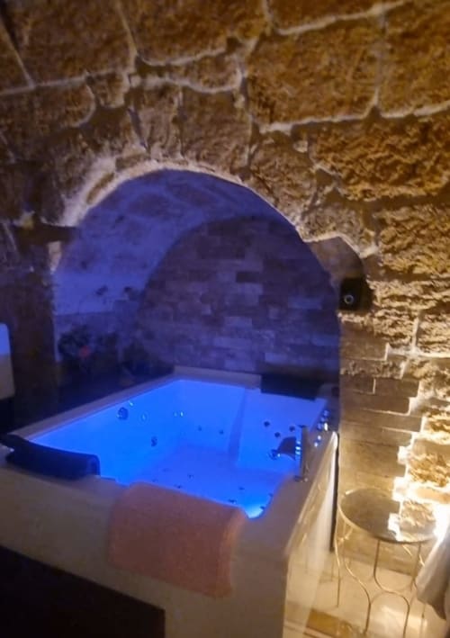 Illuminated blue Jacuzzi tub in stone-walled apartment at CorteLirice Paradiso, Italy