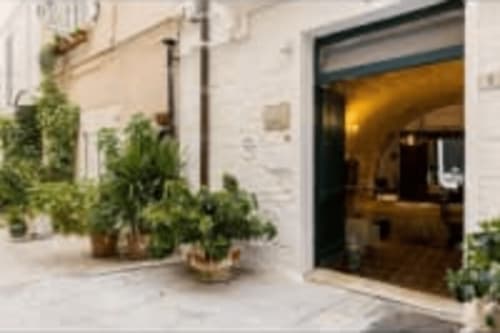 CorteLirice Paradiso entrance with potted plants and open doorway revealing warmly lit interior, Sottano 2 apartment