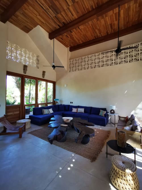 Amplia sala de estar en villa Kaab Kaan House, Tulum, con sofá seccional azul marino, vigas de madera y vistas al océano