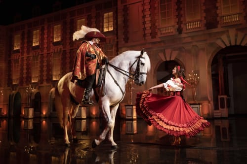 Scène élégante à La Maison D'olivier : cavalier en costume sur cheval blanc avec femme en robe rouge