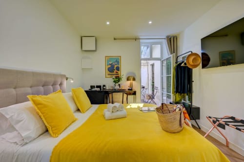 Luminosa camera standard del Boutique Hôtel Provencia Marsiglia con biancheria gialla, testata neutra e moderna scrivania
