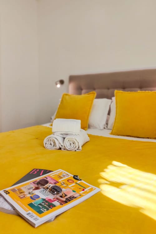 Camera Standard luminosa al Boutique Hôtel Provencia di Marsiglia con biancheria gialla, asciugamani bianchi arrotolati e rivista sul letto