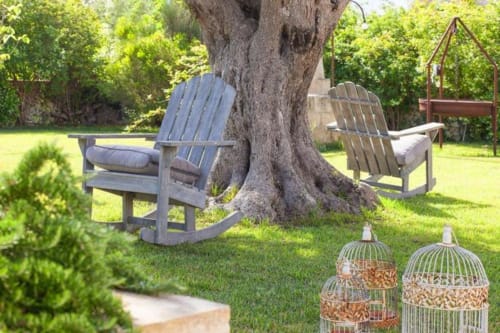 Coin de détente ombragé à la Masseria Vittoria avec chaises Adirondack sous un arbre centenaire, Acaya, Italie