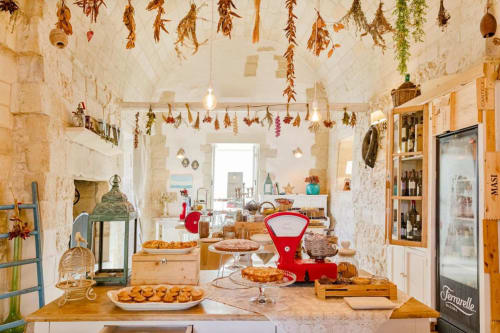 Cucina rustica italiana a Masseria Vittoria con erbe aromatiche essiccate appese, tavoli in legno con prodotti da forno e specialità locali