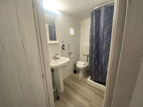 Bagno moderno con lavabo su colonna, toilette e doccia con tenda a motivi neri presso l'appartamento Newhouse a Bari