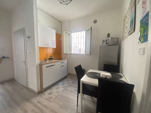 Cucina e zona pranzo dell'appartamento moderno Newhouse a Bari con schienale arancione, elettrodomestici in acciaio inox e finestra con vista sulla città