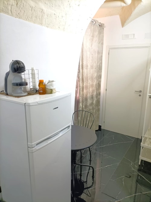 Piccola camera studio all'hotel Newhouse di Bari con frigorifero, macchina caffè, tavolo, sedia e porta