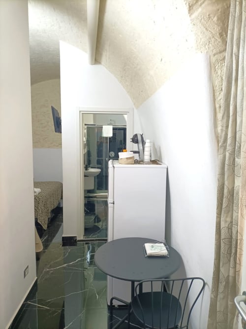 Camera compatta dell'Newhouse Bari con scrivania, sedia nera, ingresso bagno specchiato e pavimento in marmo