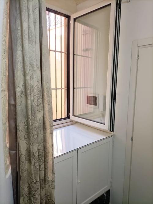Finestra moderna dell'hotel Newhouse Bari con cornice bianca, vista città, tende patterned e controlli climatici