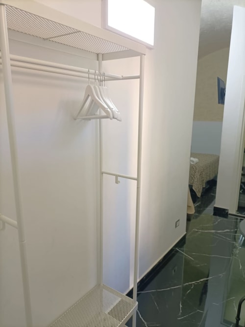 Camera d'hotel Newhouse a Bari, Italia: armadio con grucce bianche e scaffale portaoggetti