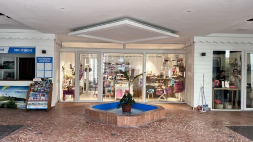 Shopping arcade at Caribluewave Appartements with retail storefronts and decorative plant in St-François, Guadeloupe