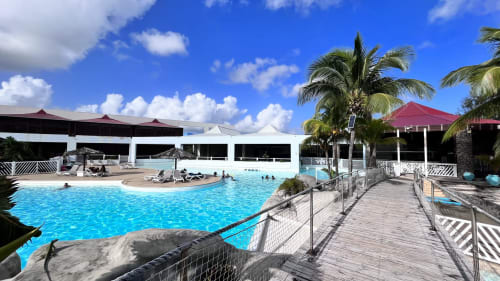 Caribluewave Appartements pool area in St-François, Guadeloupe with blue waters, palm trees, and white pavilion structures