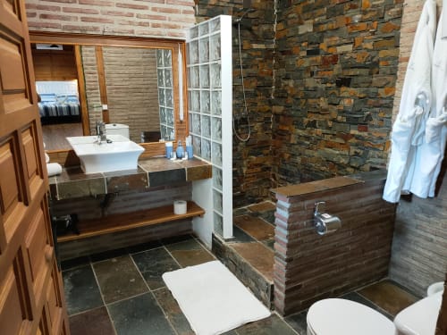 Baño lujoso en la Casita Gencianilla de El Paraje del Chef, Laroles Nevada, con paredes de ladrillo, bañera blanca y diseño moderno