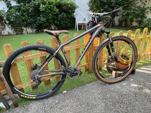 Bicicleta de montaña estacionada en el soleado jardín de los apartamentos Tessa en Matadepera con cerca de madera y césped verde