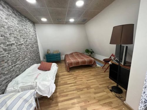 Dormitorio amplio en apartamentos Tessa en Matadepera con dos camas, pared de ladrillo, pisos de madera y vista al jardín