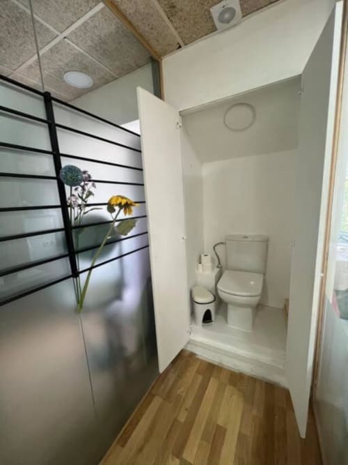 Baño moderno con inodoro blanco y bidé en el apartamento de Tessa en Matadepera, con flores decorativas visibles a través del vidrio