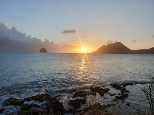 Coucher de soleil sur la côte caraïbe : la femme couchée, le Rocher du Diamant, le Morne Larcher créent une toile magique, fusion de beauté naturelle et d'émerveillement