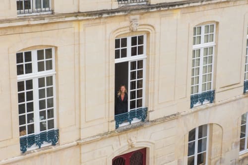Femme à la fenêtre d'un immeuble de style parisien crème, Villa République Normandie, chambre d'hôtes à Caen, France