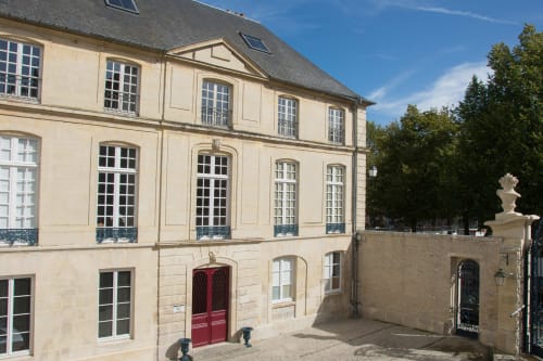 Villa République Normandie, une demeure historique de couleur crème à Caen avec toit mansardé et porte d'entrée rouge