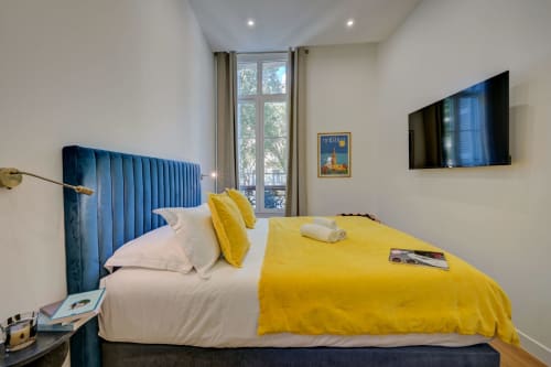 Camera superior con testata in velluto blu, biancheria gialla, TV a schermo piatto e vista sulla città presso Boutique Hôtel Provencia