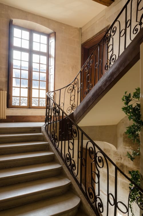 Escalier courbe élégant avec rampes en fer forgé et main courante en bois à la Villa République Normandie, Caen