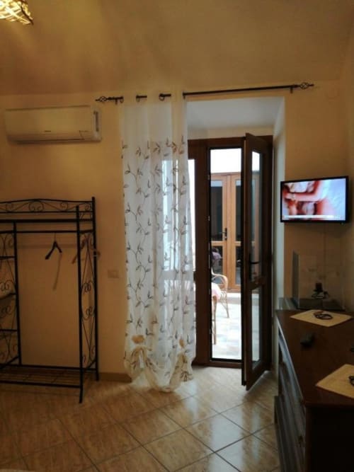 Camera da letto di Zia Amalia Villa Asfodelo ad Alghero con letto in ferro, tende trasparenti e porte in legno scuro