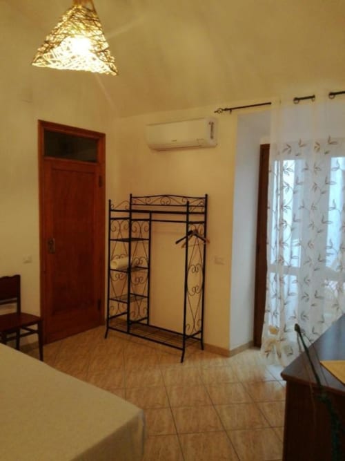 Camera Asfodelo di Zia Amalia Villa ad Alghero con letto in metallo, pareti gialle, porta rossa e comfort moderni