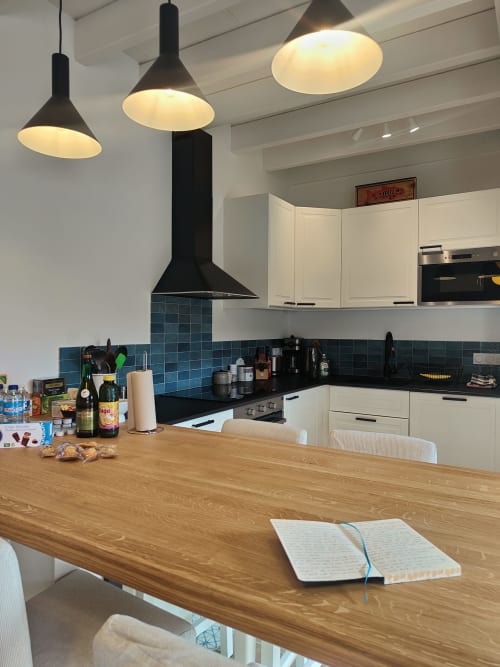 Cuisine moderne avec armoires blanches, plan de travail noir, crédence turquoise et table de salle à manger en bois au Studio Centre Audrey, Dinan