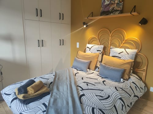 Chambre studio à La Conciergerie de Nathalie à Dinan avec mur accent jaune, tête de lit tissée et parure de lit à motifs