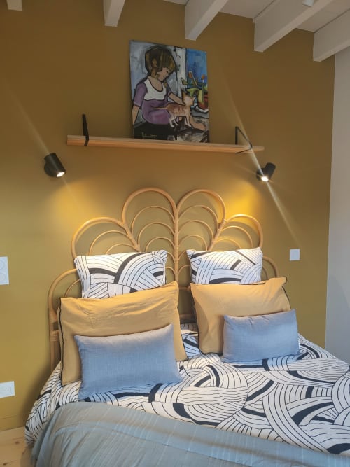 Chambre studio cosy à La Conciergerie de Nathalie à Dinan avec tête de lit tissée, literie à motifs et œuvre d'art au-dessus du bois