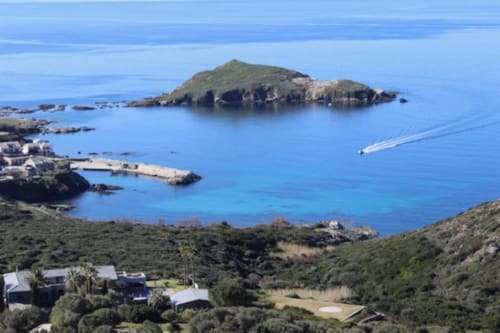 Vue aérienne des îles rocheuses de Centuri et des eaux turquoise méditerranéennes avec La Conciergerie du Cap Corse nichée dans la verdure