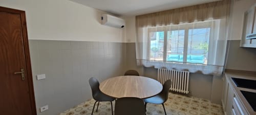 Zona pranzo moderna con tavolo rotondo, vista lago, angolo cottura e servizi accessibili a Villa Italia